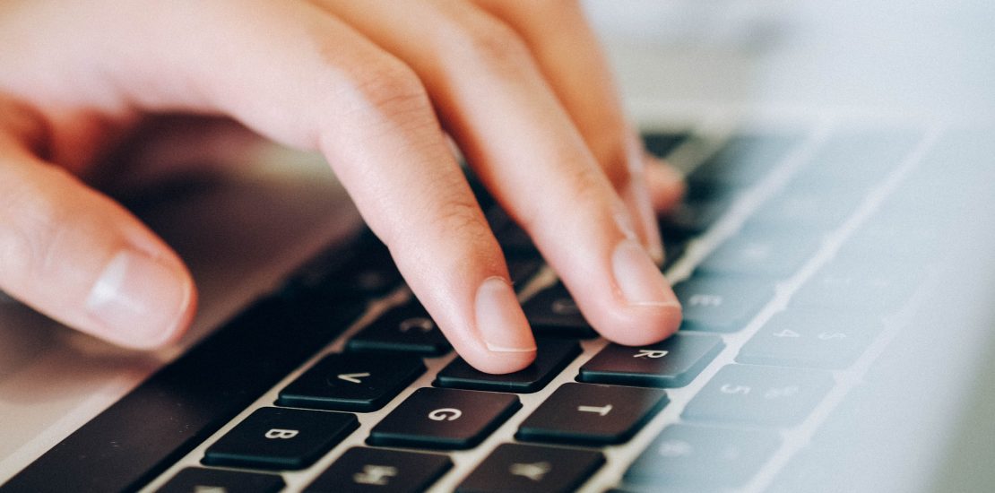 A close up of hands typing on a laptop keyboard
