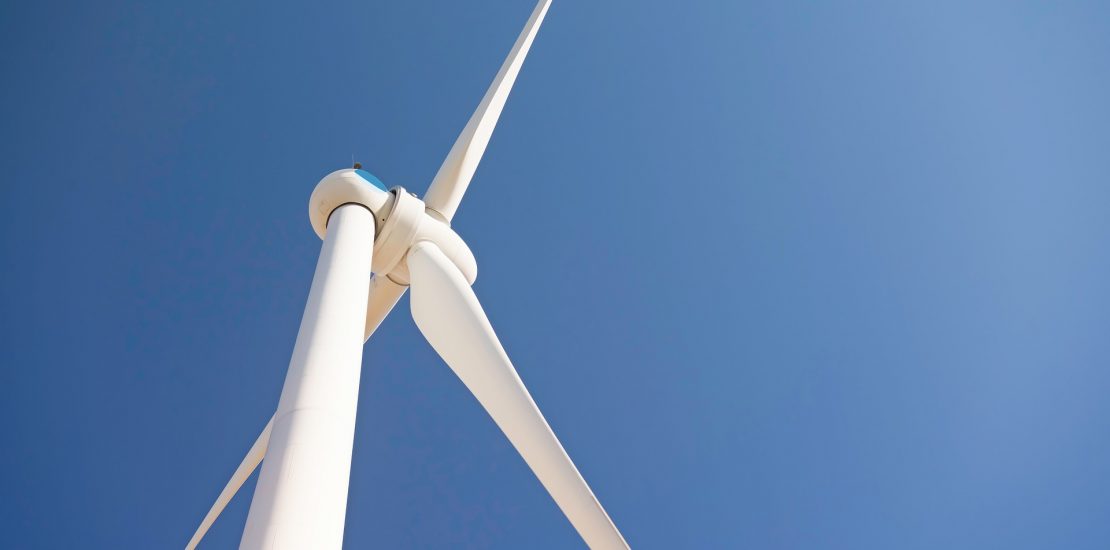 close up of a wind turbine looking upwards to blue sky