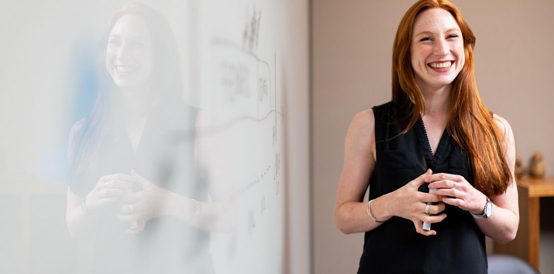 A young woman stands in front of a whiteboard