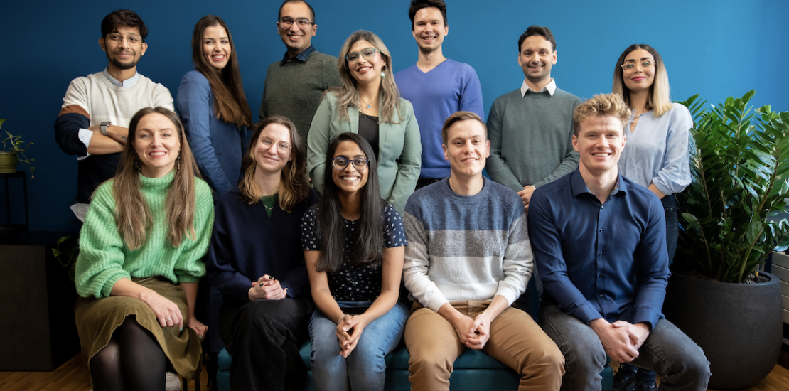 Smiling team members at Oxyle in front of a blue coloured wall