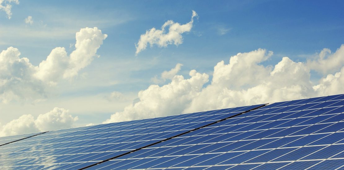 close up of solar energy panels with blue sky and clouds in the background