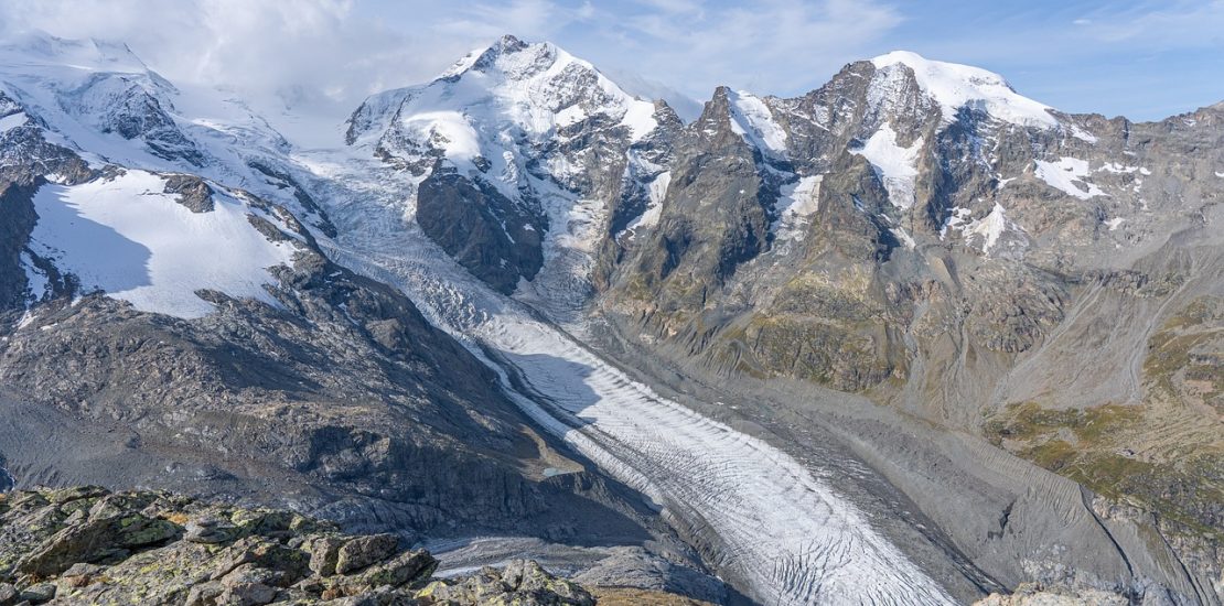 far away shot of a glacier nestled in snow capped mountains