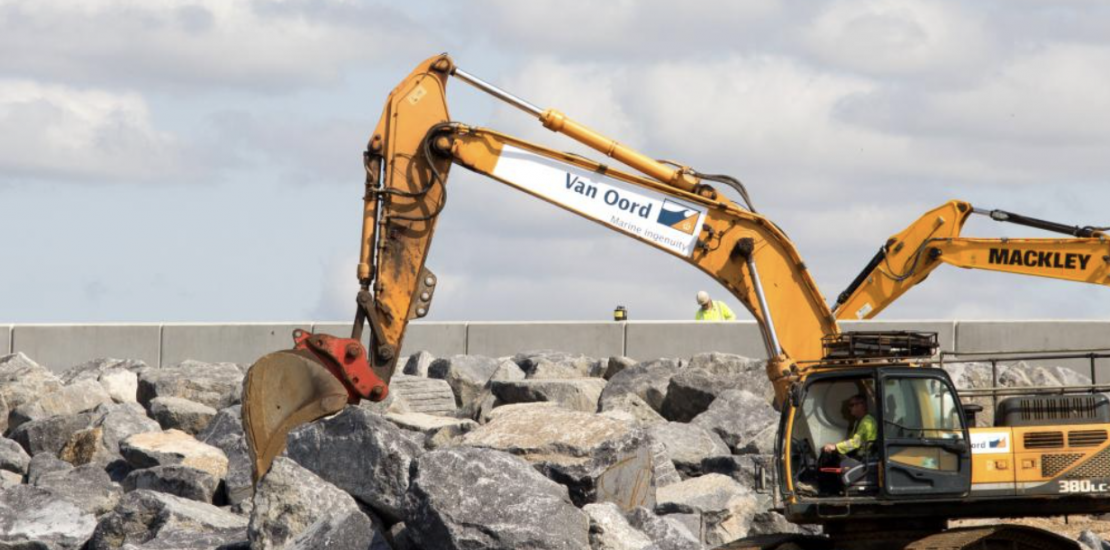 a yellow van oord digger removing giant rocks