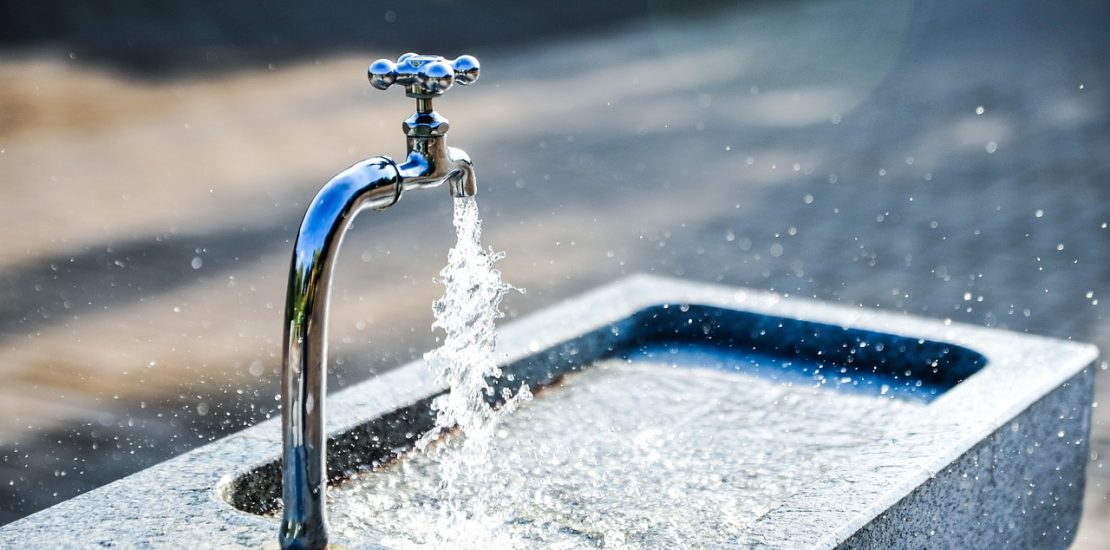 Water coming out of an outside tap. It is a sunny day